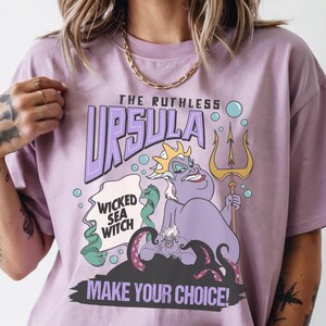 A person wearing a pink t-shirt with a graphic design featuring a character from the Disney animated film "The Little Mermaid".