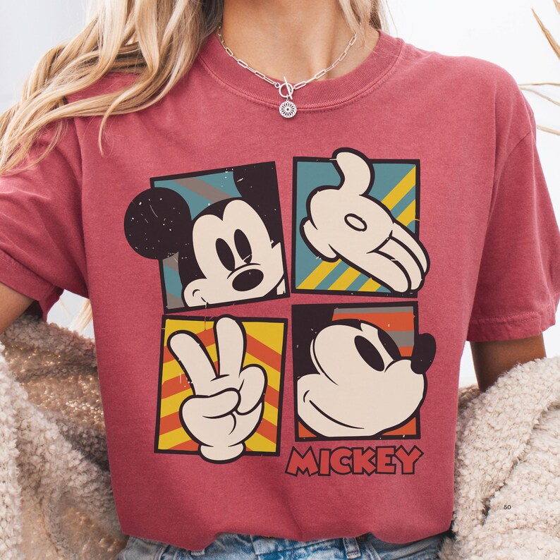 A person wearing a red t-shirt with a graphic design featuring Mickey Mouse and the peace sign.