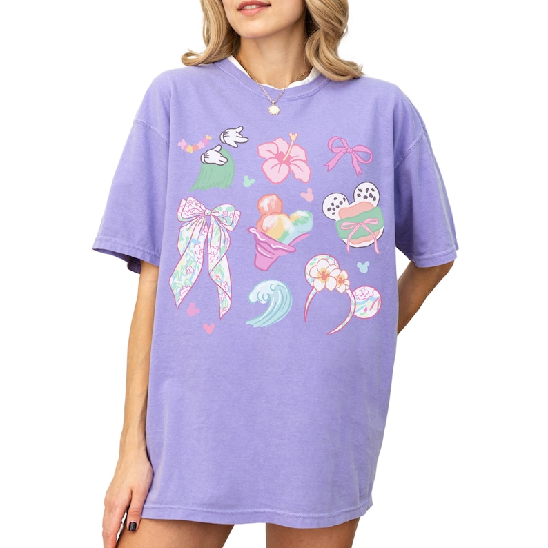 A woman wearing a purple dress with various colorful and whimsical illustrations, including flowers, bows, and other decorative elements.