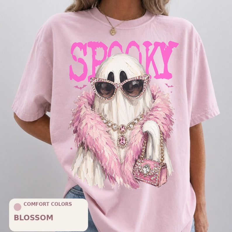 A pink t-shirt with a graphic design of a ghost wearing sunglasses, a pink fur coat, and a pink purse.