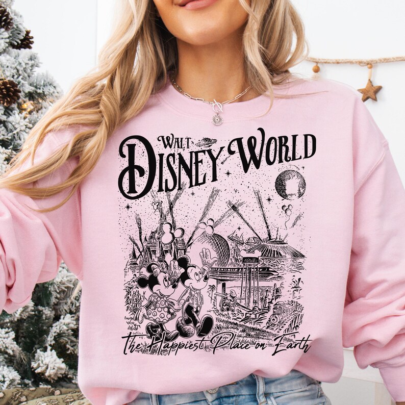 A woman wearing a pink sweatshirt with a graphic design featuring Disney characters and the text "Walt Disney World" printed on it.