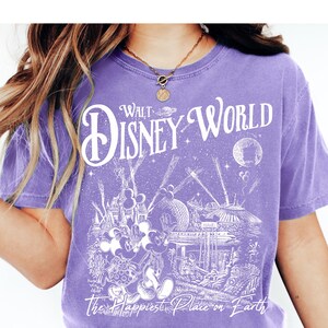 A person wearing a purple t-shirt with a Disney World logo and various Disney characters printed on it.
