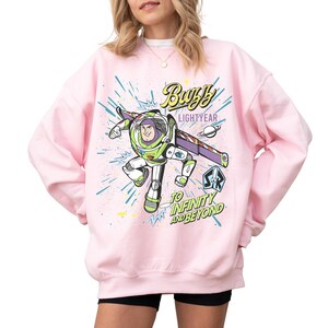A woman wearing a pink sweatshirt with a graphic of Buzz Lightyear from the Toy Story franchise.