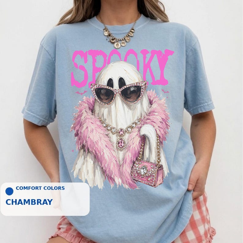 A person wearing a blue t-shirt with a graphic design of a ghost wearing sunglasses, a pink feathered scarf, and holding a pink purse.