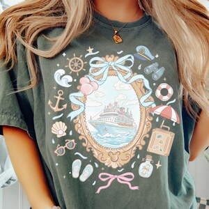 A person wearing a green t-shirt with a colorful graphic design depicting a cruise ship, various nautical elements, and a decorative frame.