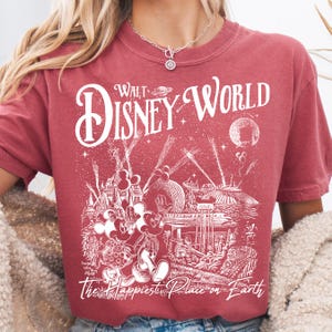 A person wearing a red t-shirt with a graphic design depicting Disney World and the text "Walt Disney World" printed on it.
