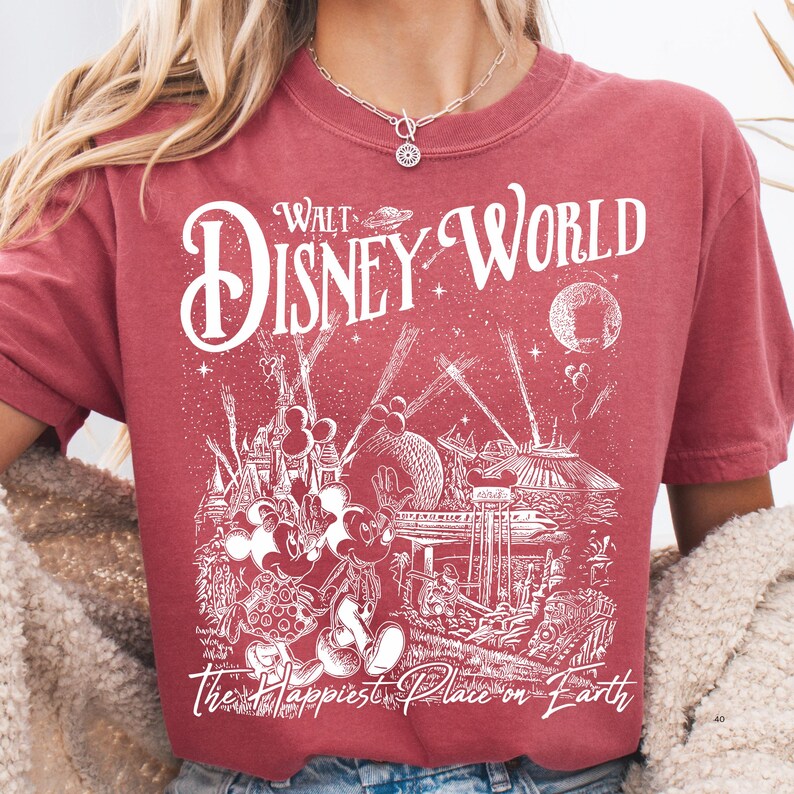 A person wearing a red t-shirt with a graphic design depicting Disney World and the text "Walt Disney World" printed on it.