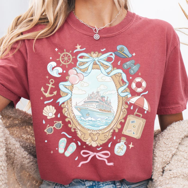 A woman wearing a red t-shirt with a graphic design featuring a ship, anchor, and various nautical elements.