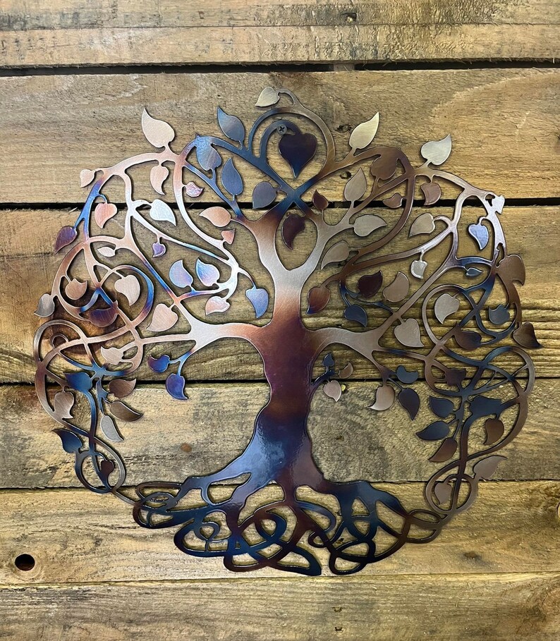 Op de afbeelding: Een metalen wanddecoratie in de vorm van een levensboom met ingewikkelde takken en wortels. De boom is geschilderd in tinten blauw, paars en bruin, wat een verloop cre&euml;ert.