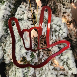 May include: Red metal Christmas ornament shaped like the American Sign Language symbol for "I love you".
