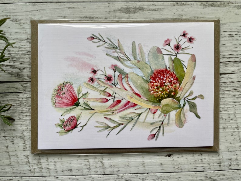 Op de afbeelding: Een aquarel schilderij van een boeket roze en rode bloemen met groene bladeren. De bloemen zijn in een losse, natuurlijke stijl gerangschikt. De achtergrond is een zachte, aquarel was van roze en blauw.