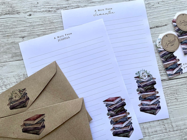 May include: Two white lined stationery note cards with the text "A Note From Joshua" and "A Note From Samantha" printed on them. Each card features a stack of books with a floral design on top. The cards are accompanied by two brown envelopes with a stack of books design on the front.