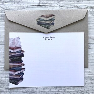 Puede incluir: Una pila de libros antiguos con un sobre de papel marr&oacute;n. El sobre tiene una pila de libros m&aacute;s peque&ntilde;a encima. La tarjeta de felicitaci&oacute;n dice "A Note From Jonah".