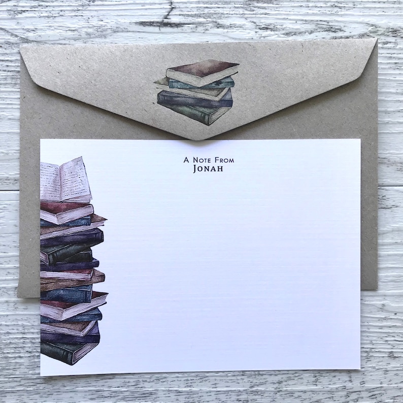 Puede incluir: Una pila de libros antiguos con un sobre de papel marr&oacute;n. El sobre tiene una pila de libros m&aacute;s peque&ntilde;a encima. La tarjeta de felicitaci&oacute;n dice "A Note From Jonah".