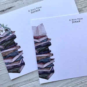 Puede incluir: Dos tarjetas blancas con una ilustraci&oacute;n de una pila de libros. La tarjeta superior dice "A Note From Sophie" y la tarjeta inferior dice "A Note From Jonah".