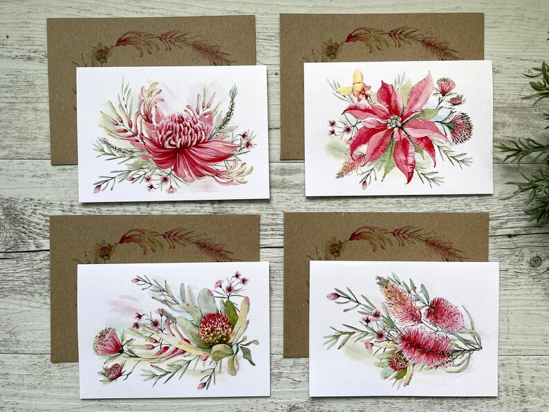 Op de afbeelding: Set van vier blanco wenskaarten met aquarel illustraties van roze en rode Australische inheemse bloemen. De kaarten zijn gedrukt op wit karton en hebben bruine enveloppen.