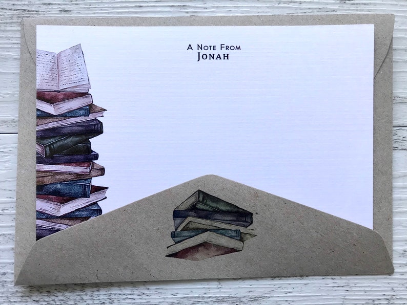 Puede incluir: Una tarjeta blanca con una solapa de sobre marr&oacute;n. La tarjeta tiene una pila de libros en el lado izquierdo y el texto "A Note From Jonah" en la parte superior. La solapa del sobre tiene una pila de libros en la parte inferior.