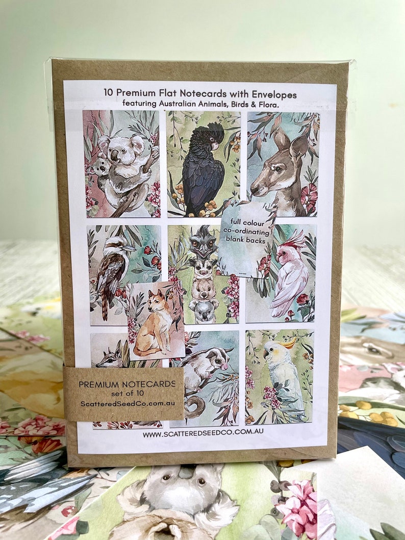 May include: A set of 10 premium flat notecards with envelopes. The cards feature colorful illustrations of Australian animals, birds, and flora. The packaging includes the text "Premium Notecards" and "ScatteredSeedCo.com.au".