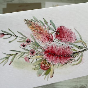 Op de afbeelding: Waterverf schilderij van een boeket roze en rode flessenborstel bloemen met groene bladeren.