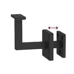 May include: Black metal handrail bracket with adjustable width. The bracket has a square base and a vertical arm that extends to a horizontal arm. The bracket is designed to be mounted to a wall.