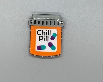 May include: Orange pill bottle with a silver lid and the words "Chill Pill" printed on the front. Two purple and teal pills are visible inside the bottle.