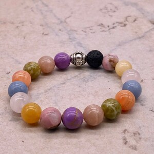 May include: A colorful beaded bracelet with a silver and black bead in the center. The bracelet features beads in shades of pink, purple, orange, yellow, green, and blue.