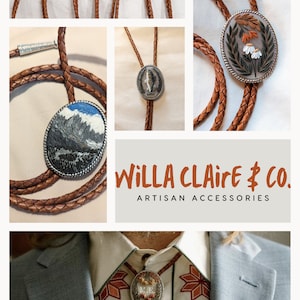 K&ouml;nnte beinhalten: Eine Sammlung von Bolo-Krawatten mit verschiedenen Designs, darunter eine Bergszene, ein Fisch und ein Blumenmuster. Die Bolo-Krawatten sind aus braunem Lederband und silberfarbenen Metallakzenten gefertigt. Der Text "WILLA CLAIRE & CO. ARTISAN ACCESSORIES" ist unter den Bolo-Krawatten abgebildet.