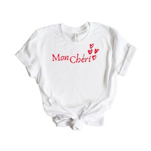 May include: White t-shirt with red text that says "Mon Ch&eacute;ri" and red hearts.