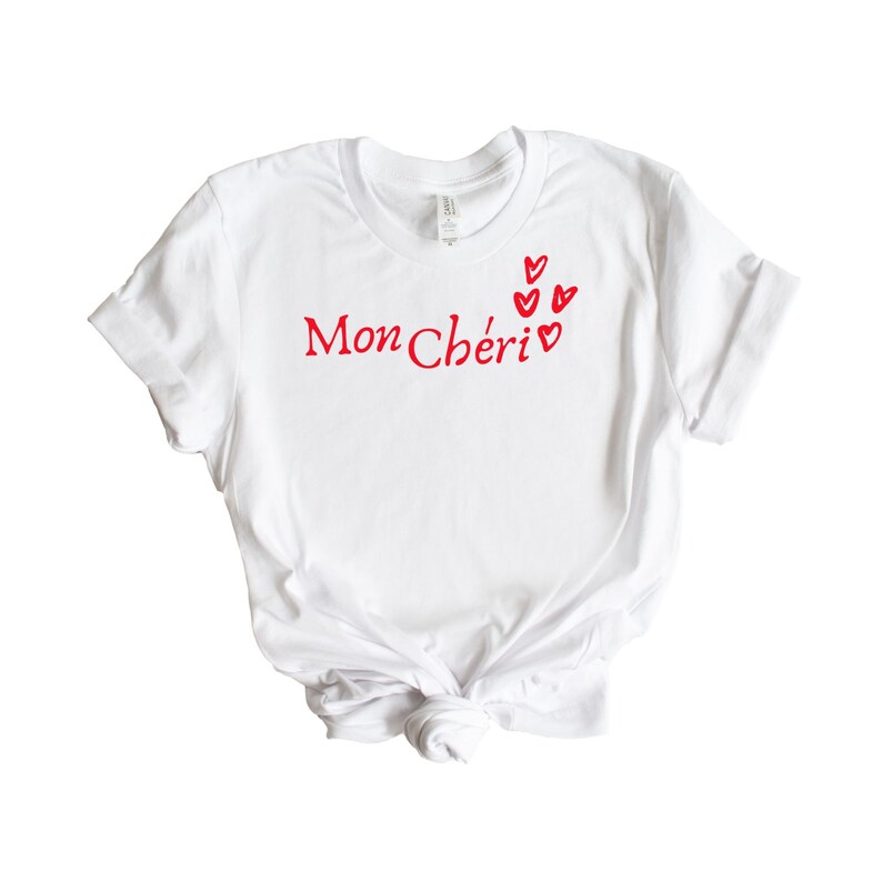 May include: White t-shirt with red text that says "Mon Ch&eacute;ri" and red hearts.