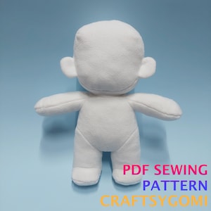 May include: A white plush doll body with arms, legs, and ears. The doll is made of a soft, textured fabric and is standing upright against a light blue background. Text on the bottom right reads "PDF SEWING PATTERN CRAFTSYGOMI."