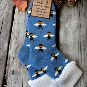 May include: A pair of blue socks with a white and yellow bee pattern. The socks have a white cuff and are made of combed cotton. The socks are labeled "Cool, Comfortable, Combed Cotton Socks, Fun for feet" and "Jess & Lou".