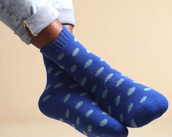 Puede incluir: Un par de calcetines azules con un patrón de óvalos azul claro. Los calcetines están hechos de un material suave. La persona que lleva los calcetines también lleva vaqueros azules.