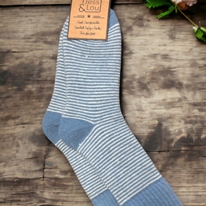 Op de afbeelding: Blauw-wit gestreepte sokken met een geribbelde boord en hiel. Het etiket toont "Jess & Lou" en "Cool, Comfortable, Comfy Cotton Socks, Fun for feet."