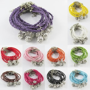 May include: A set of 10 colourful braided leather bracelets with silver volleyball charm pendants. Each bracelet is made of multiple strands of braided leather in a variety of colours, including purple, pink, red, orange, green, white, blue, black, brown, and yellow.