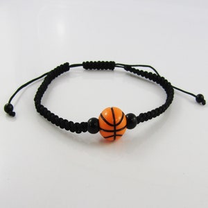 May include: Black braided bracelet with an orange basketball charm.