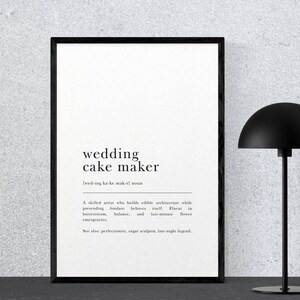 May include: A framed print with the words "wedding cake maker" in a minimalist black and white design. A black desk lamp with a rounded shade stands to the right of the frame.