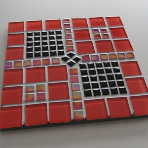 Pode incluir: Um mosaico de azulejos vermelhos e pretos com um padrão geométrico. O mosaico é feito de pequenos azulejos quadrados dispostos em um padrão de grade. O mosaico é um bom exemplo de uma obra de arte de mosaico.