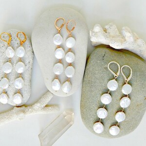 A pair of earrings with four flat white cultured pearls
