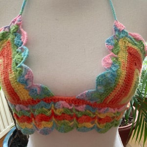 May include: A rainbow crochet halter top with a scalloped edge. The top is made with a variety of colors, including pink, blue, green, yellow, and orange.