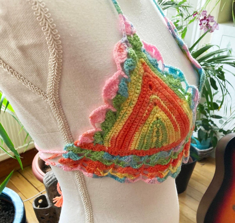 May include: A colorful crocheted halter top with a rainbow striped pattern and scalloped edges.