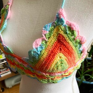May include: A rainbow crochet top with a scalloped edge. The top is made of a soft, colorful yarn and has a unique, bohemian style.