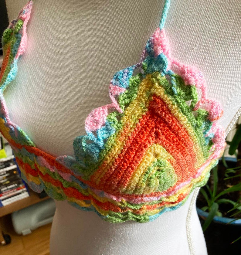 May include: A rainbow crochet top with a scalloped edge. The top is made of a soft, colorful yarn and has a unique, bohemian style.