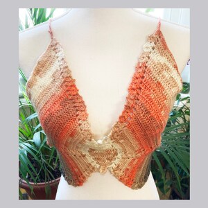 May include: A crocheted halter top with a deep V-neckline. The top is made in a gradient of peach, brown, and white.