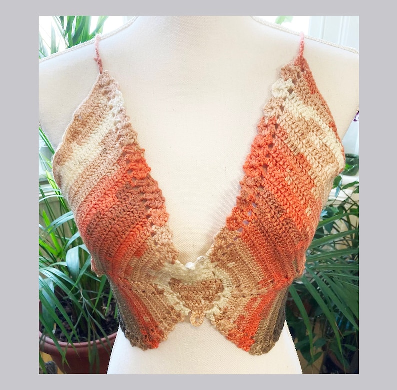 May include: A crocheted halter top with a deep V-neckline. The top is made in a gradient of peach, brown, and white.