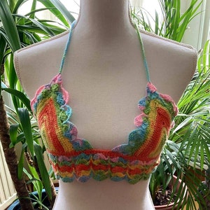 May include: A rainbow crochet top with a scalloped edge. The top is made with a variety of colors, including pink, orange, yellow, green, and blue.