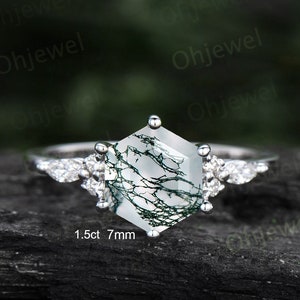 May include: A silver ring featuring a hexagonal green moss agate gemstone, measuring 7mm and 1.5ct, with smaller clear gemstones on the band.