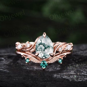 May include: A pear-shaped green moss agate engagement ring set in rose gold with a delicate leaf design and emerald green accent stones.