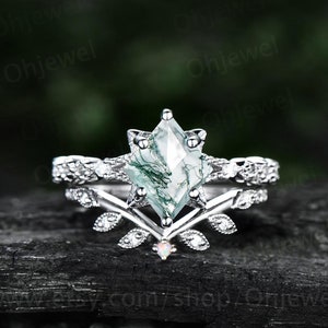 Könnte beinhalten: Ein silberner Ring mit einem grünen Moosachat-Edelstein in einer Sternform-Fassung. Der Ring ist mit kleineren Diamanten verziert und hat ein zartes Blattdesign.