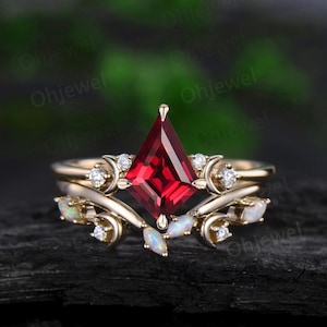 May include: A gold ring set with a red square-shaped gemstone and smaller white gemstones. The ring is accented with a delicate floral design and opal accents.