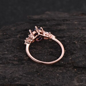 Pode incluir: Anel de noivado em ouro rosa com uma grande pedra central oval e pedras de acento menores. O anel &eacute; engastado em uma banda simples.
